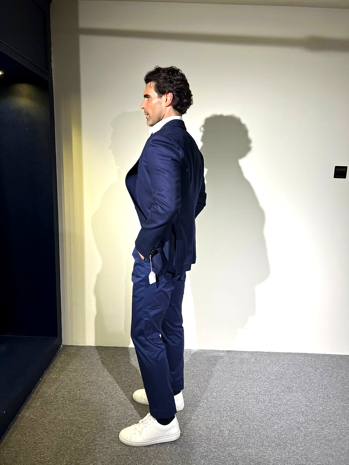 Side profile of a client in a finished navy linen suit with white sneakers