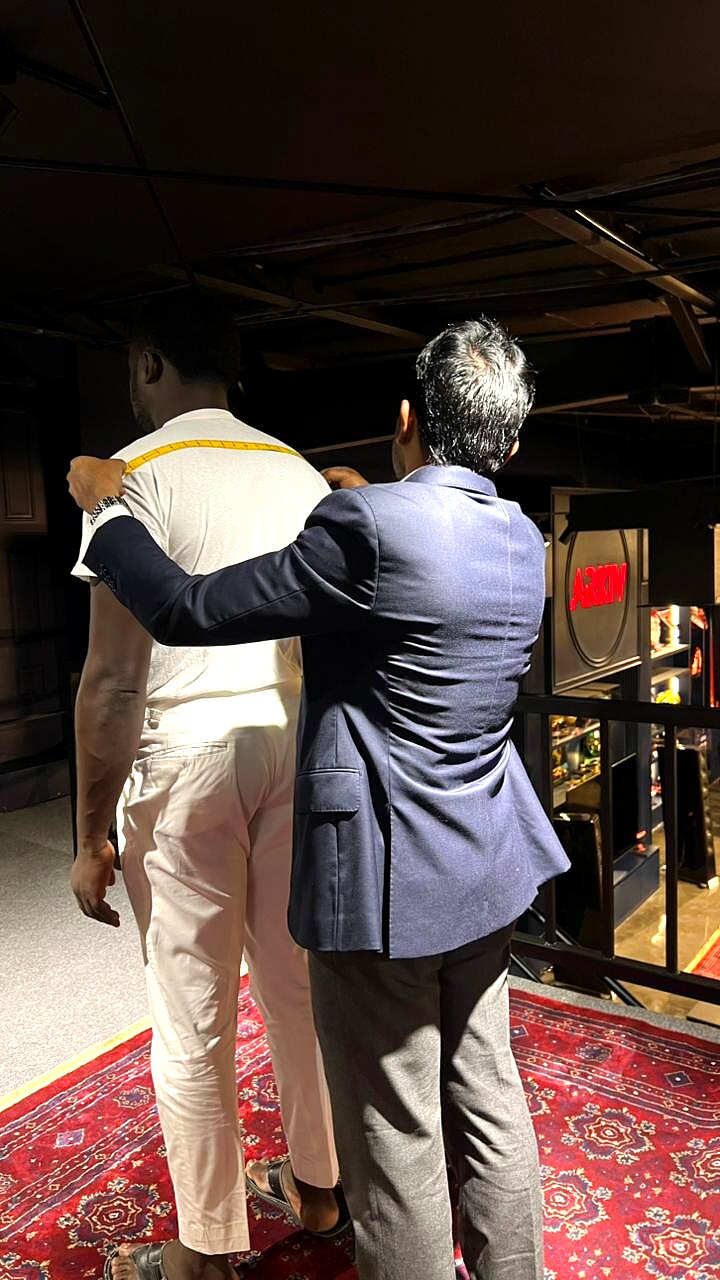 Tailor measuring back length on a client in the atelier