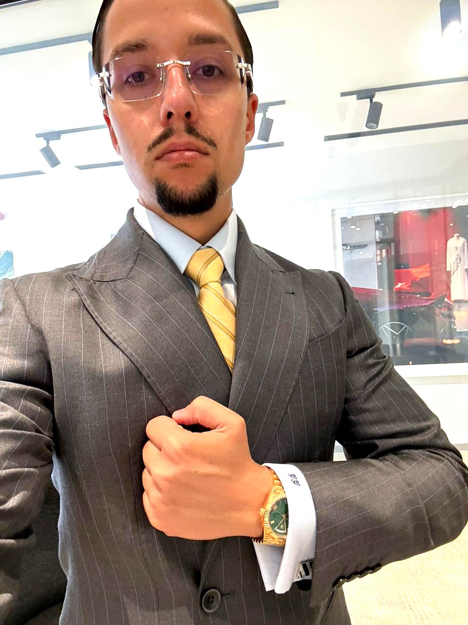 Client wearing a finished grey pinstripe double-breasted suit with gold tie