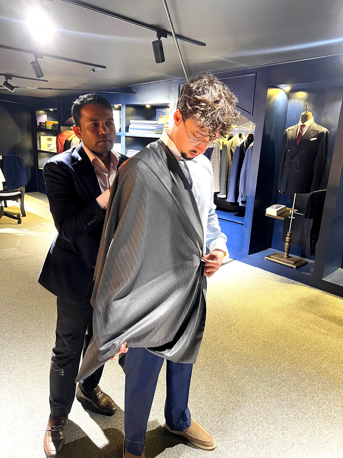 Master cutter draping shirting cloth across a client's shoulders in the atelier