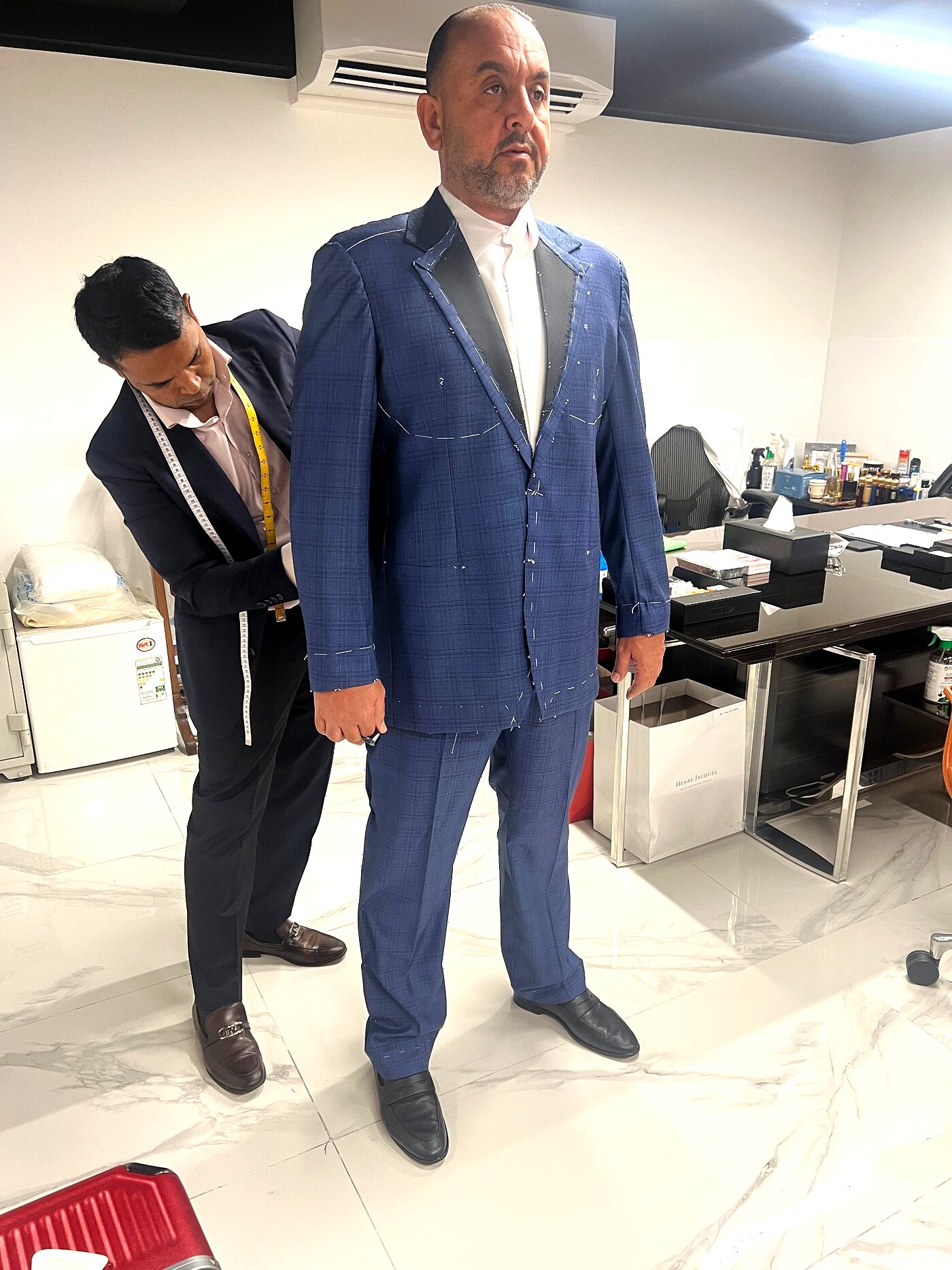 Client in a basted blue check three-piece suit covered in tailor's tacks