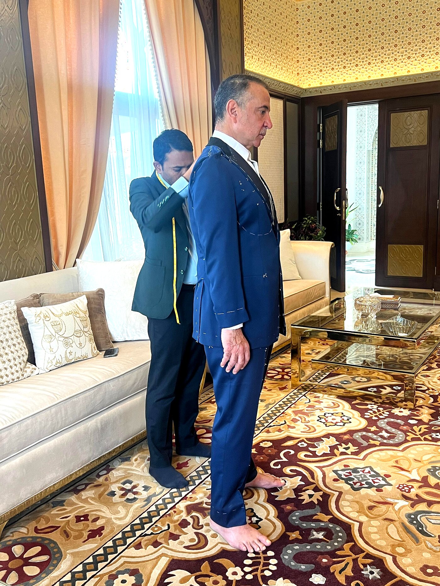 Private suite fitting — profile check of a navy basted suit