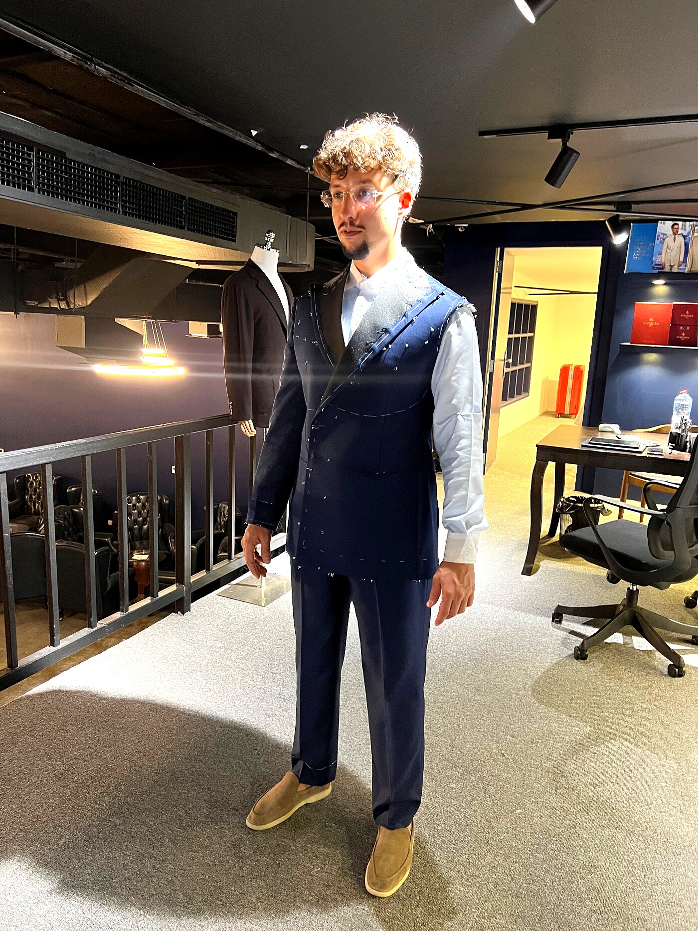 Client in a basted navy two-piece suit during a forward fitting