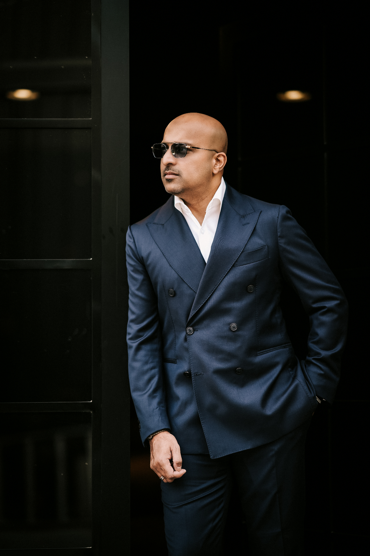 Client wearing a sharkskin navy double-breasted suit against a black door